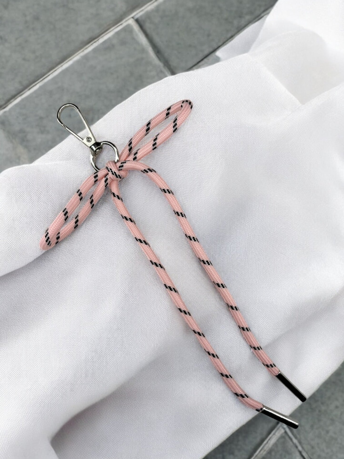 Porte clé, lacet nœud plat rose clair à traits noirs. Accessoires de décoration pour porte clés ou maroquinerie.